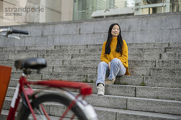 Lächelnde junge Frau sitzt auf Stufen