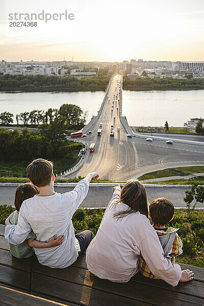 Siblings sitting on bench and looking at Volga river