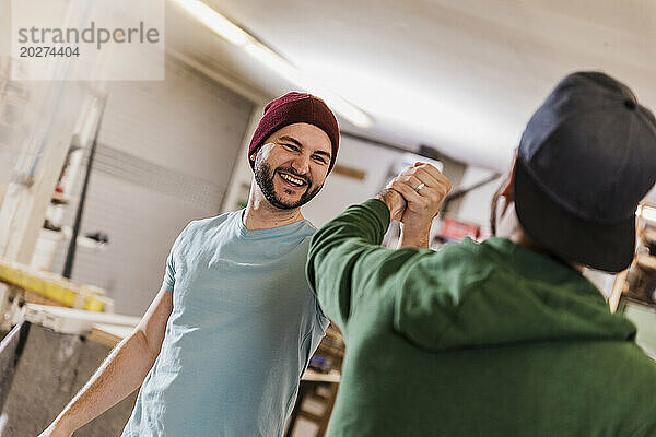 Happy craftsmen giving high-five at workshop