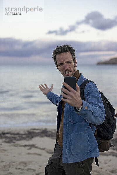 Mann macht Selfie mit Smartphone am Strand