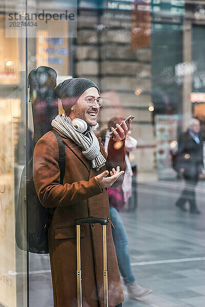 Happy man carrying guitar case and talking on smart phone