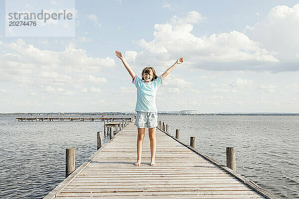Glückliches Mädchen  das auf einem Holzsteg am See steht