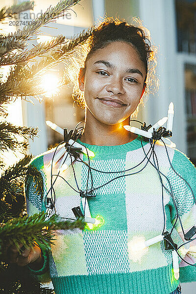 Lächelnde junge Frau mit Weihnachtsbeleuchtung