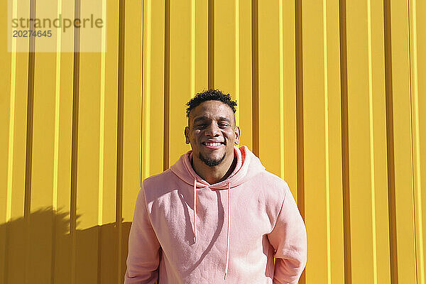 Smiling man standing in front of yellow striped wall