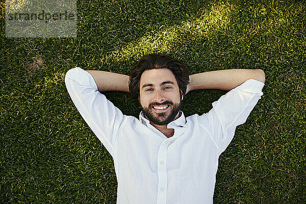 Lächelnder junger Mann  der auf Gras liegt