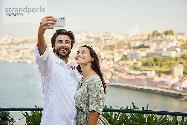 Lächelnder junger Mann  der per Smartphone ein Selfie mit einer Frau macht