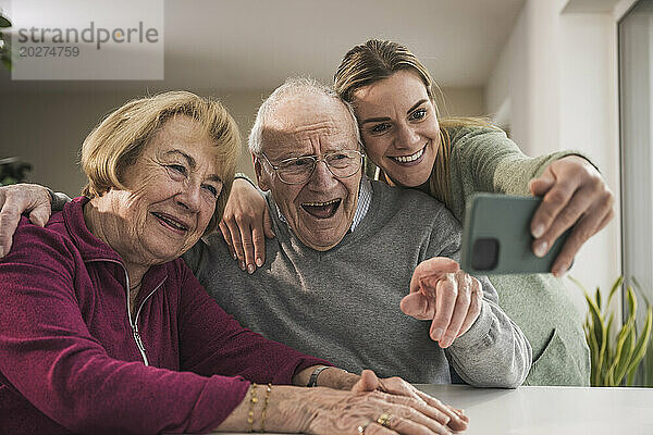 Glückliche häusliche Pflegekraft  die ein Selfie mit einem älteren Paar macht