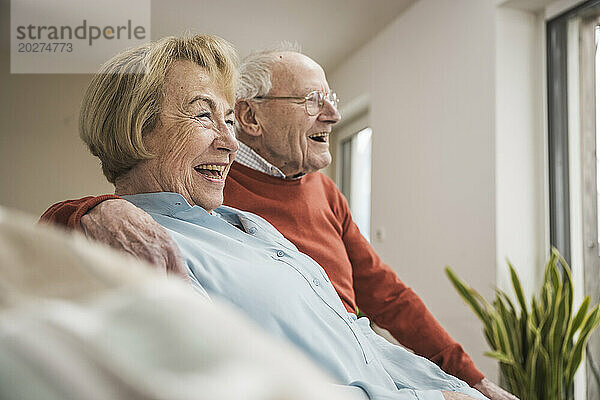 Happy senior couple sitting in living room at home