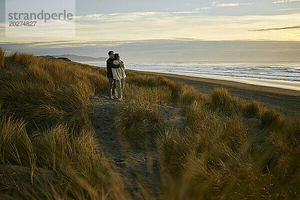 Junger Mann umarmt Freundin am Strand