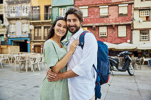 Lächelndes junges Paar  das zusammen vor Gebäuden steht