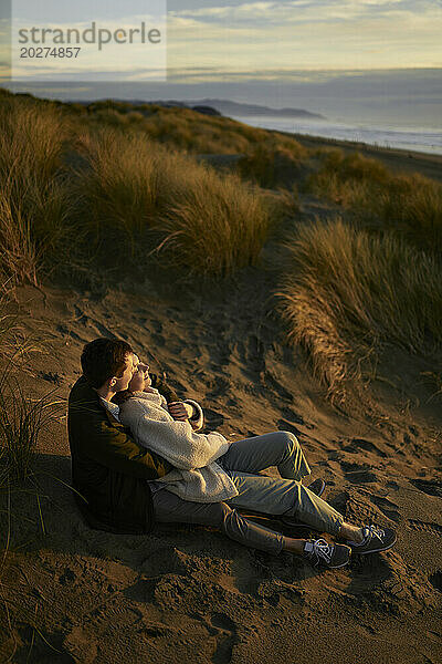 Junges Paar entspannt sich bei Sonnenuntergang am Strand