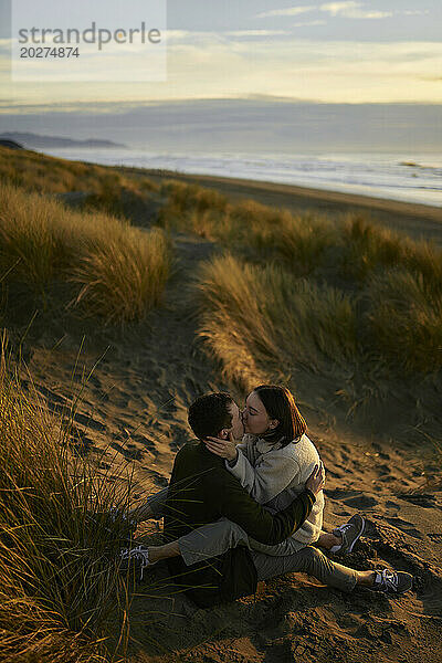 Junge Frau küsst ihren Freund am Strand