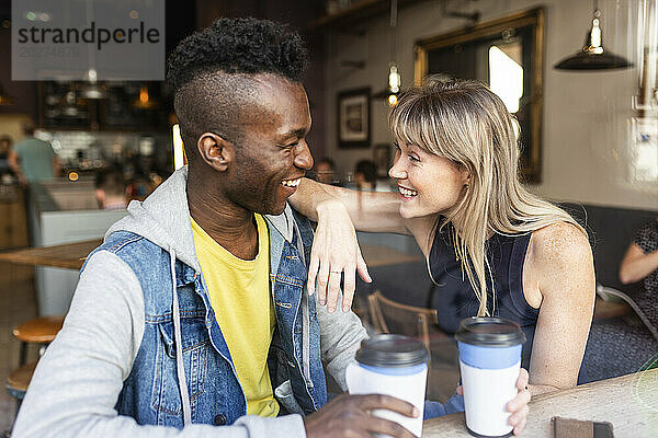 Lächelnde Frau unterhält sich mit einer Freundin  die im Café sitzt