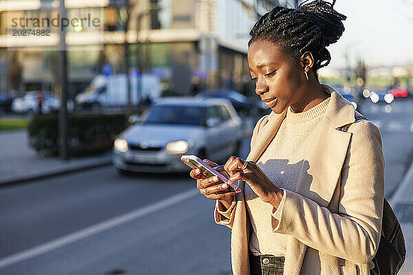 Frau benutzt Smartphone bei Sonnenuntergang auf der Straße