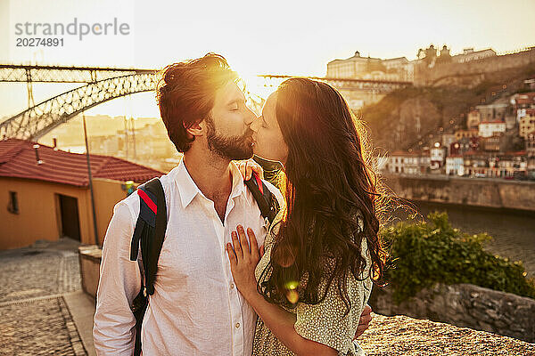 Young couple kissing in front of Dom Luis bridge  Porto  Portugal