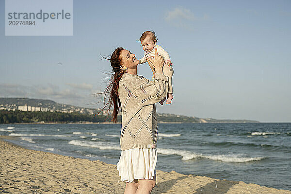 Glückliche Mutter spielt mit Tochter am Strand