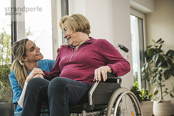 Glückliche häusliche Pflegekraft  die sich um eine ältere Frau kümmert
