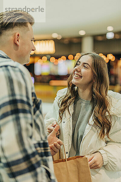 Glückliches junges Paar mit Einkaufstüten im Einkaufszentrum