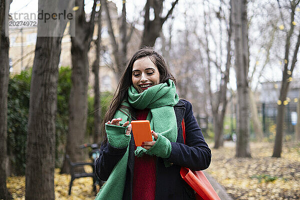 Glückliche Frau benutzt Smartphone im Park