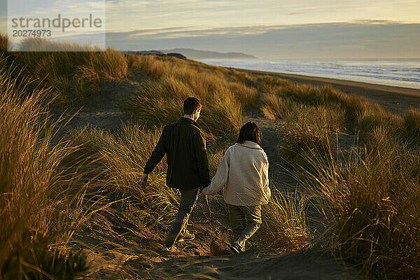 Junger Mann und Frau gehen gemeinsam am Strand spazieren