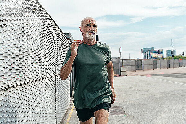 Aktiver älterer Mann joggt am Zaun
