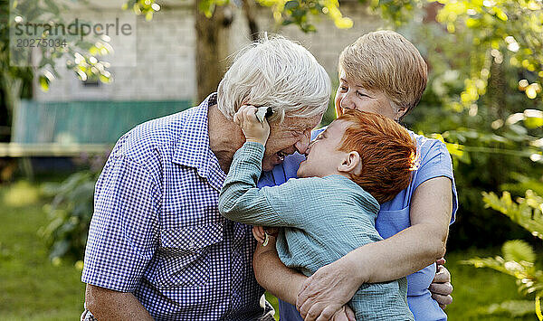 Cheerful boy playing with grandparents in garden
