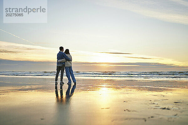 Junges Paar umarmt sich an der Küste am Meeresstrand