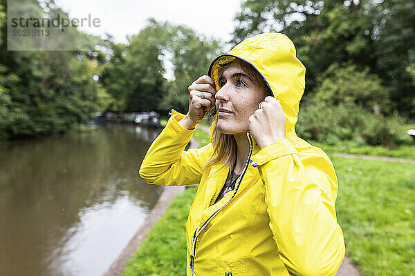 Junge Frau in gelber Jacke steht am Fluss