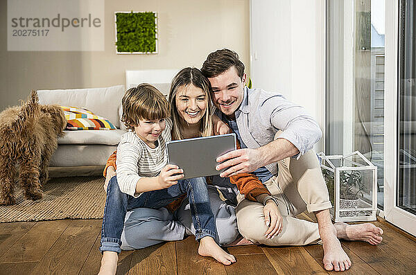 Glückliche Familie nutzt Tablet-PC und sitzt zu Hause im Wohnzimmer