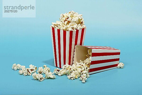 Rot gestreifter Eimer mit Popcorn auf blauem Hintergrund