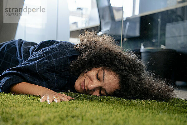 Lächelnde Geschäftsfrau  die sich im Büro auf einem Teppich ausruht