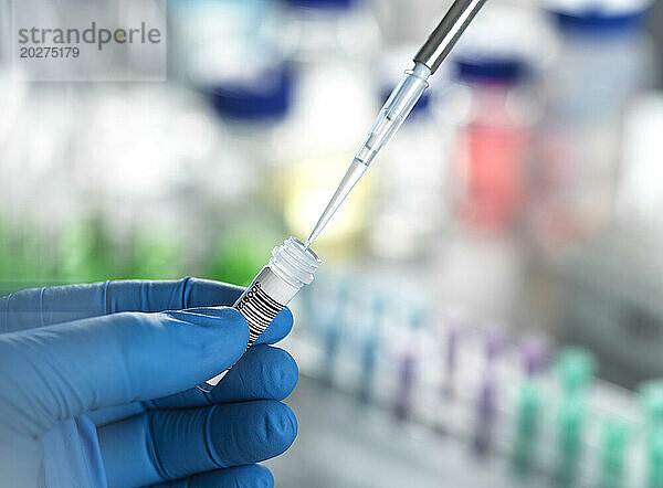 Hands of scientist pipetting DNA sample in vial at laboratory
