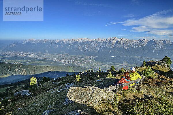 Österreich  Tirol  Zwei Wanderer machen Pause auf einer Bergbank