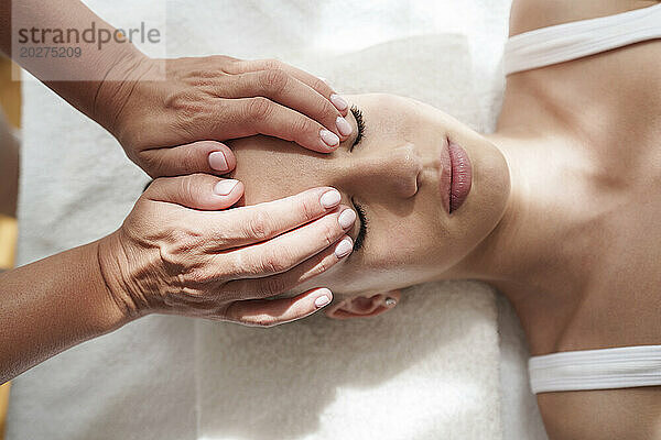 Hände des Therapeuten massieren den Kopf des Patienten im Behandlungsraum