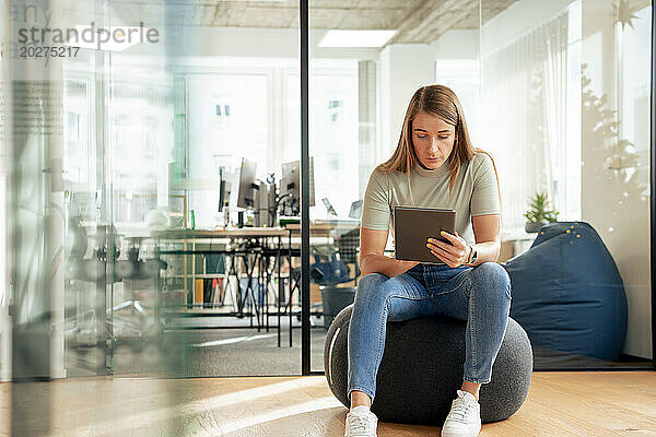 Geschäftsfrau sitzt und benutzt Tablet-PC im Büro