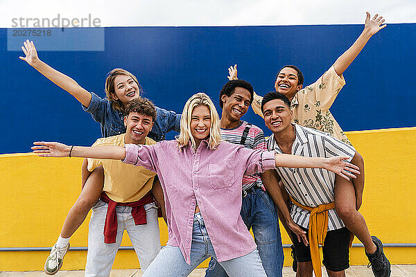 Gruppe junger Freunde in farbenfroher Kleidung posiert glücklich vor der Wand