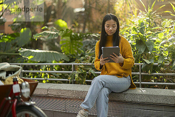 Lächelnde Frau benutzt Tablet-PC in der Nähe von Pflanzen
