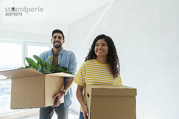 Lächelndes Paar mit Kartons im neuen Zuhause