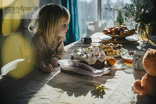 Girl staring at cake on dining table at home