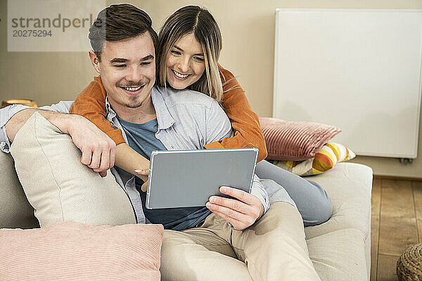Happy couple using tablet PC at home