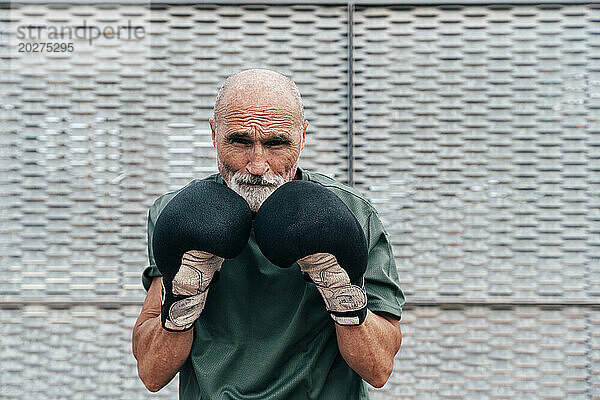 Selbstbewusster älterer Mann übt mit Boxhandschuhen