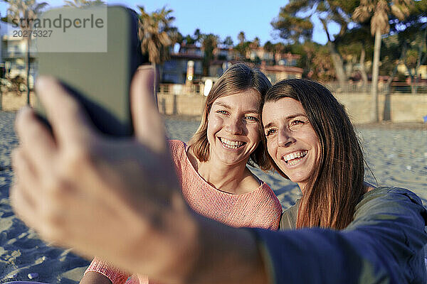 Fröhliche Freunde machen am Wochenende am Strand gemeinsam ein Selfie