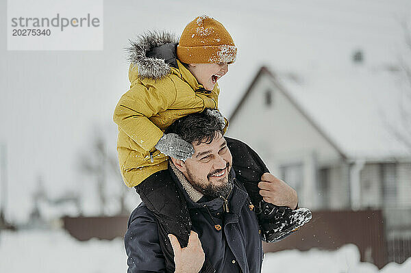 Glücklicher Vater  der im Winter seinen Sohn auf den Schultern trägt