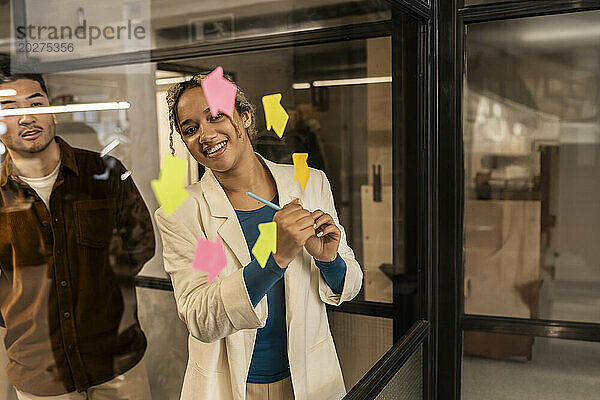 Lächelnde junge Geschäftsfrau beim Brainstorming eines Kollegen im Büro