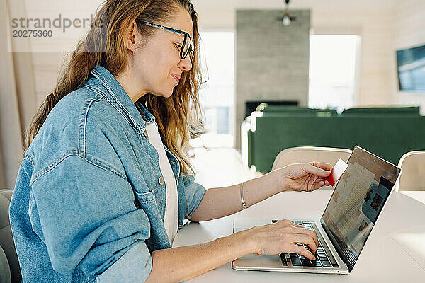 Frau mit Kreditkarte  die zu Hause online per Laptop bezahlt