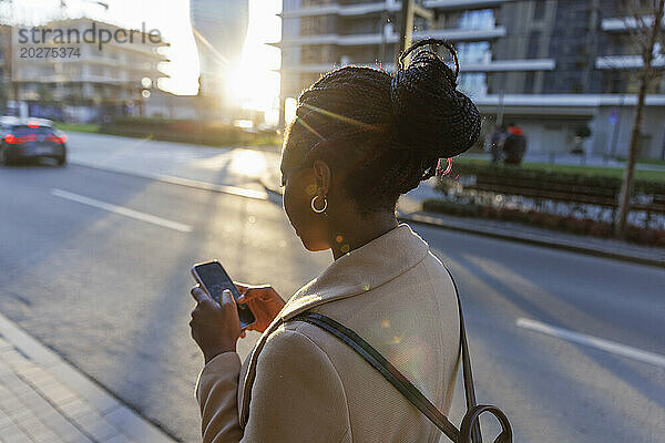 Frau benutzt Smartphone in der Stadt bei Sonnenuntergang