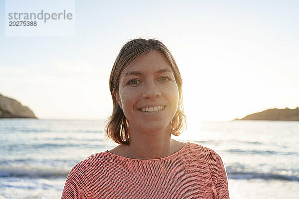 Glückliche Frau verbringt ihre Freizeit am Strand bei Sonnenuntergang