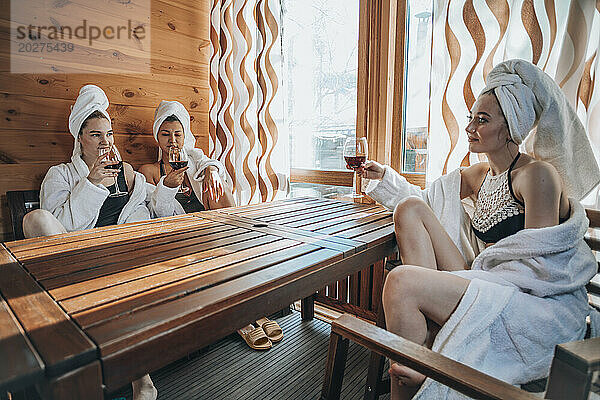 Junge Freunde genießen Wein am Tisch in der Sauna