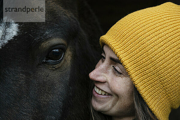 Lächelnde Frau mit geschecktem Pferd im Stall