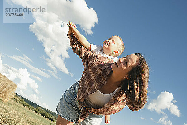 Glückliche Mutter und Sohn spielen an einem sonnigen Tag auf dem Feld